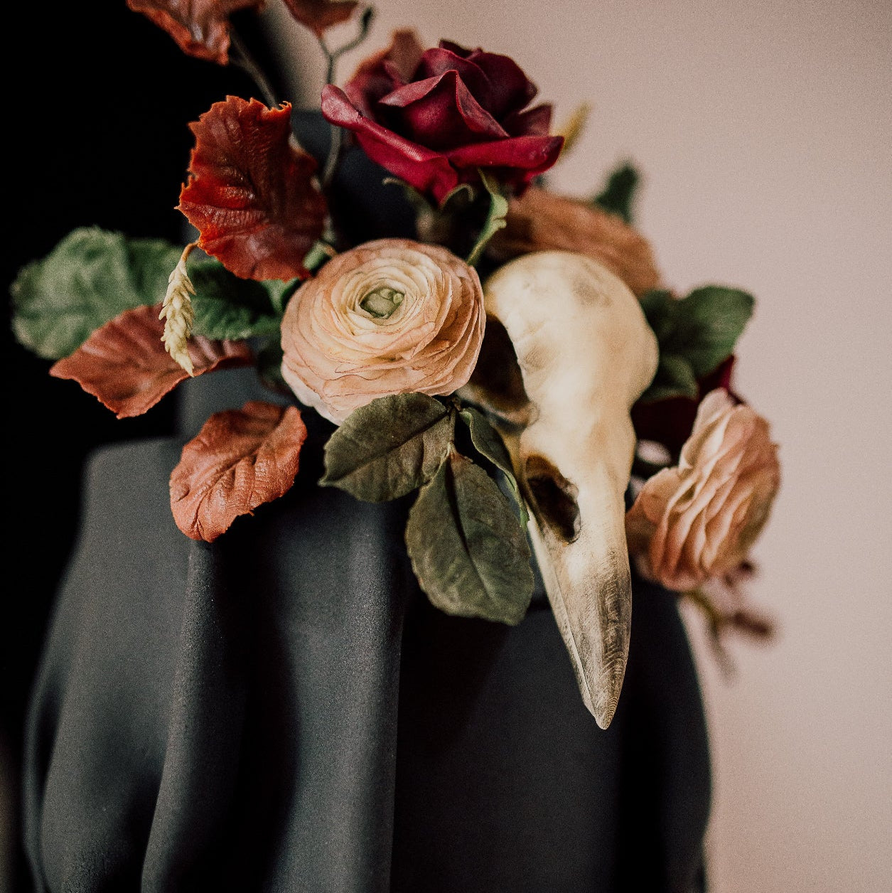 Black cake with floral decoration and a skull on top against a neutral background