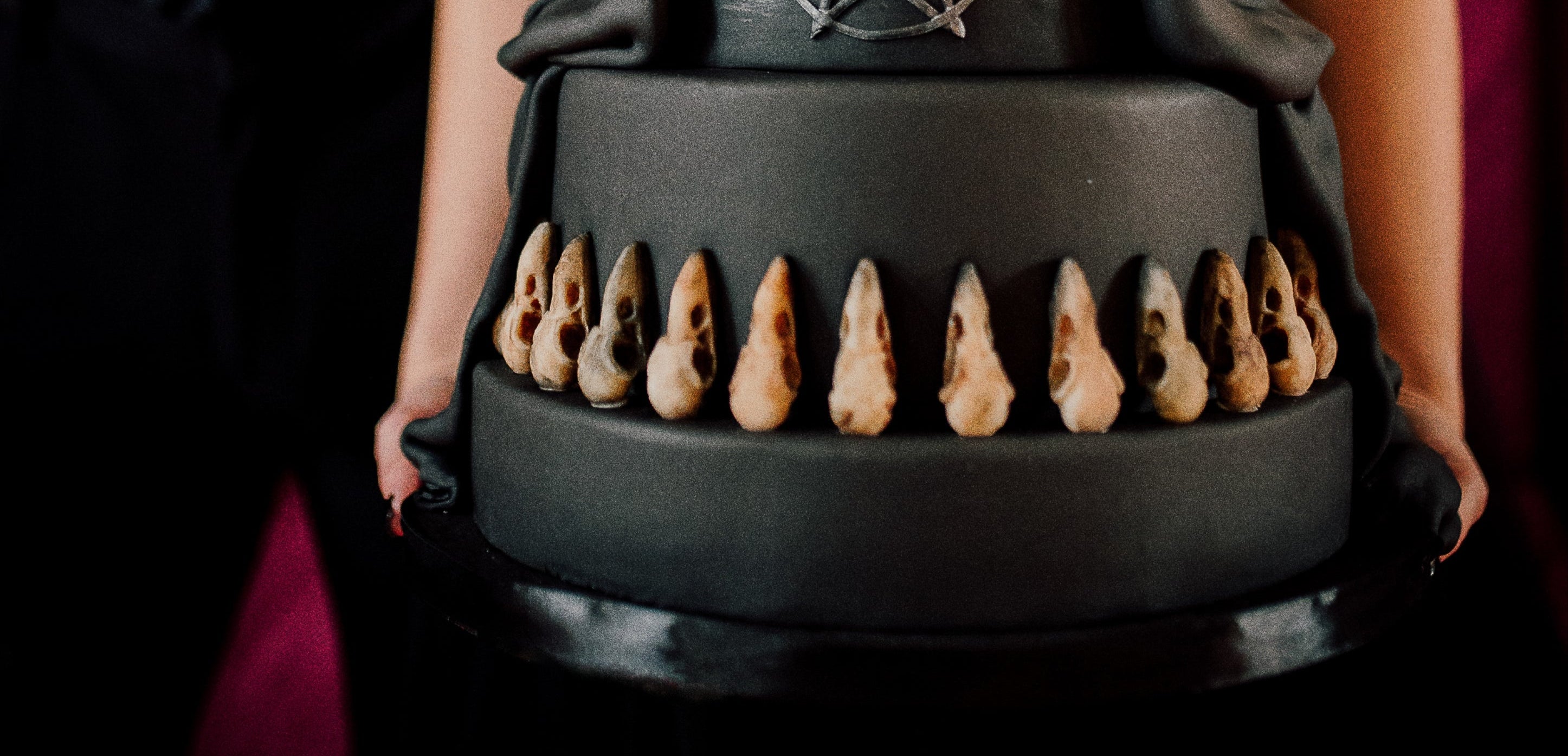 Black wedding cake with decorative elements held by a person